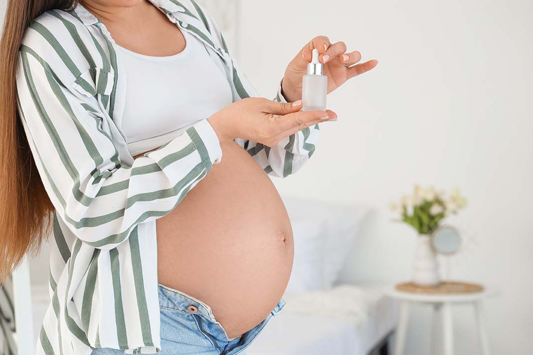 Stock image of a pregnant woman holding a skincare product